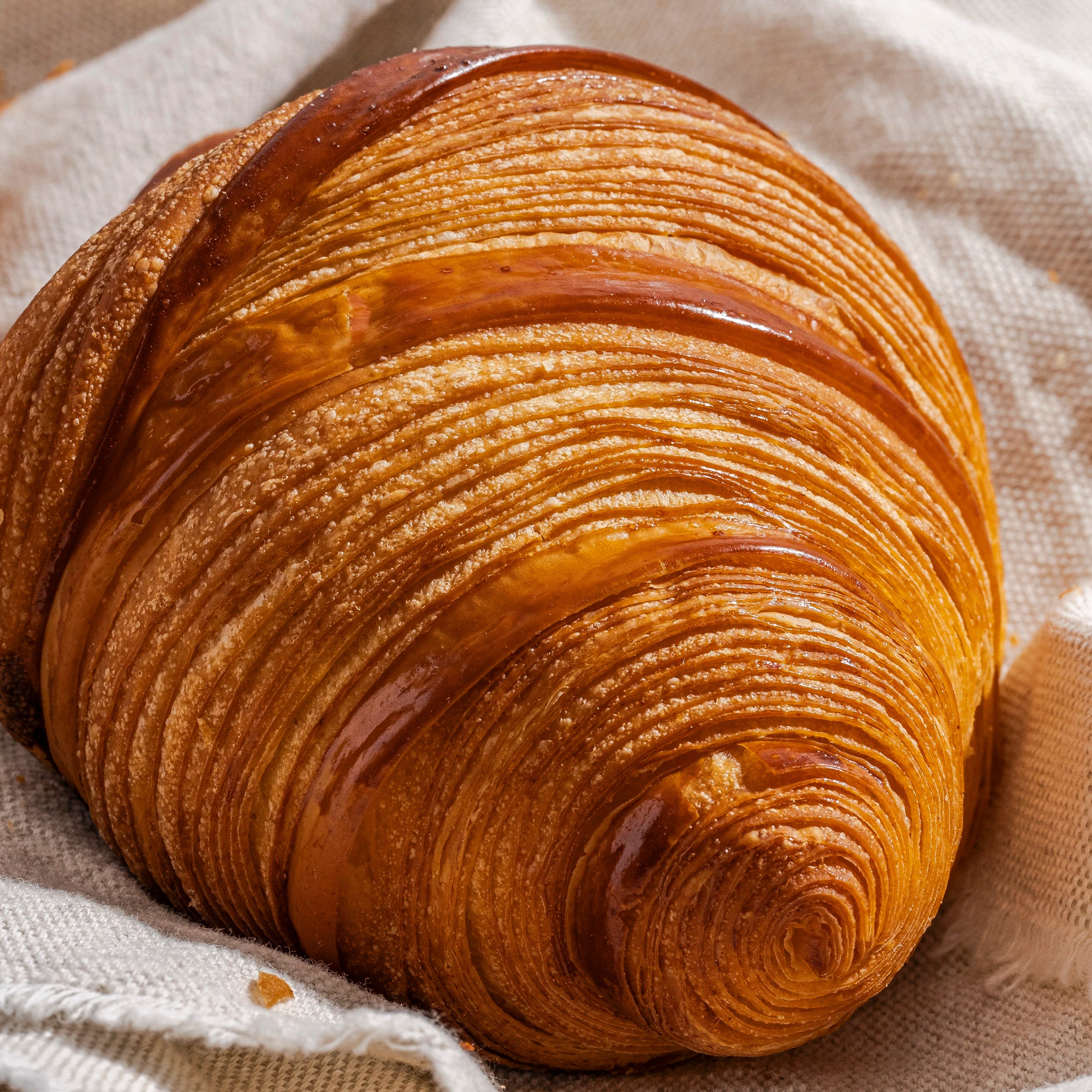 Gros plan sur les lignes parfaites et dorées du feuilletage d'un croissant au beurre Jeffrey Cagnes Paris
