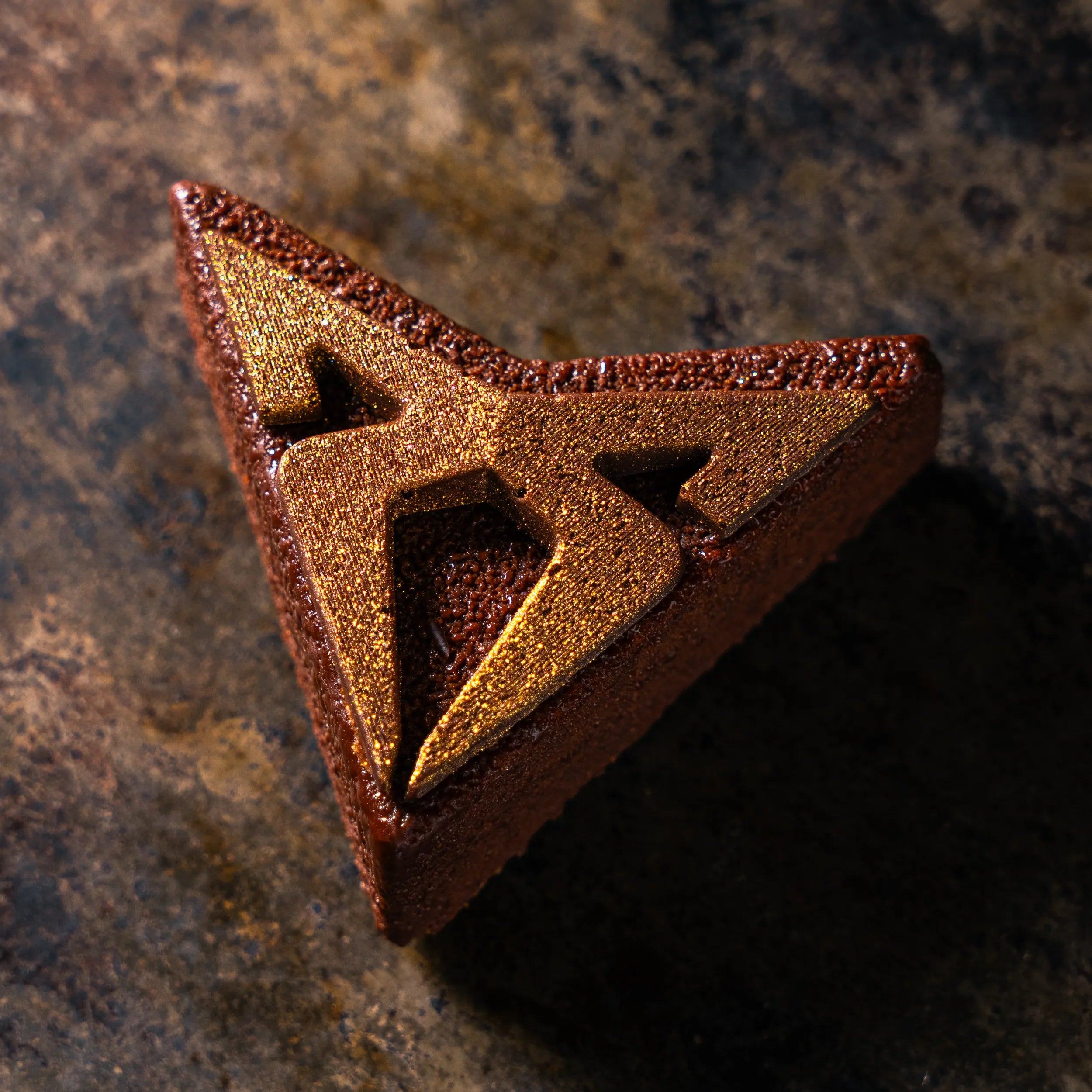 Entremets signature Cupra au chocolat noir par le Chef Jeffrey Cagnes, reprenant la forme géométrique du logo Cupra soulignée d'une élégante texture dorée.