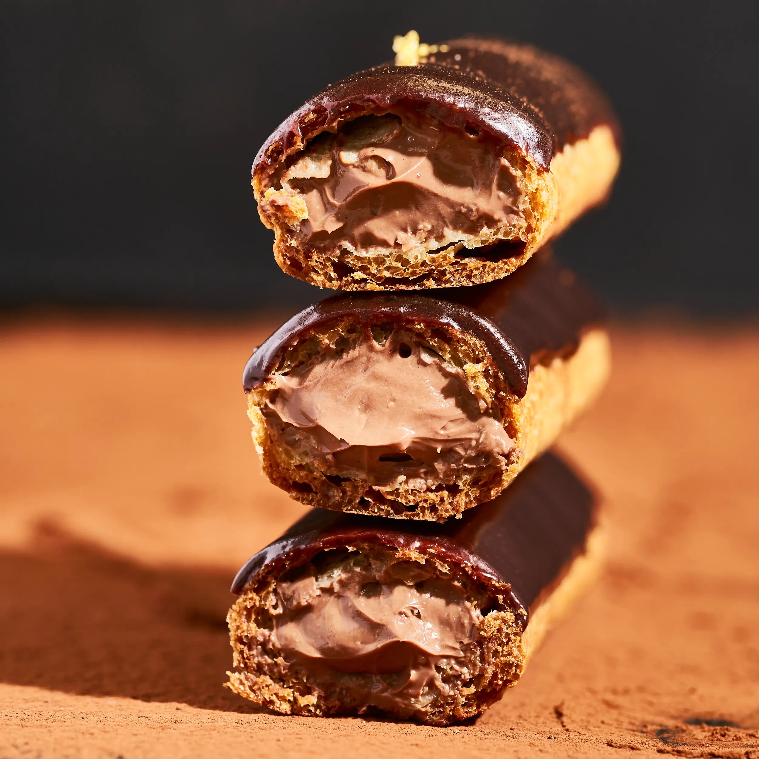 Empilement de trois demi-éclairs au chocolat montrant la régularité et l'onctuosité de la crème pâtissière au chocolat.