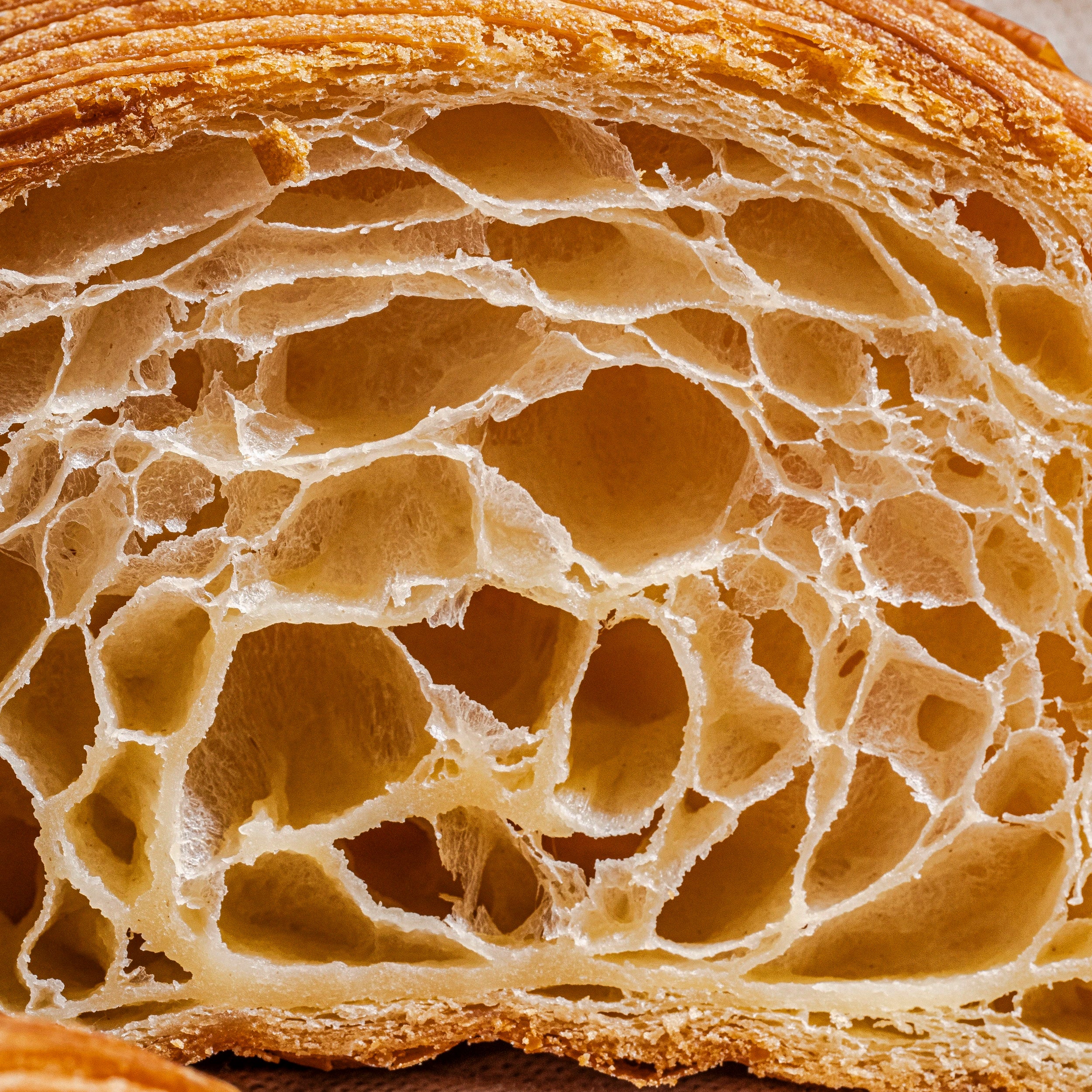 Zoom macro sur la mie parfaitement alvéolée, légère et aérée de l'intérieur d'un croissant Jeffrey Cagnes.