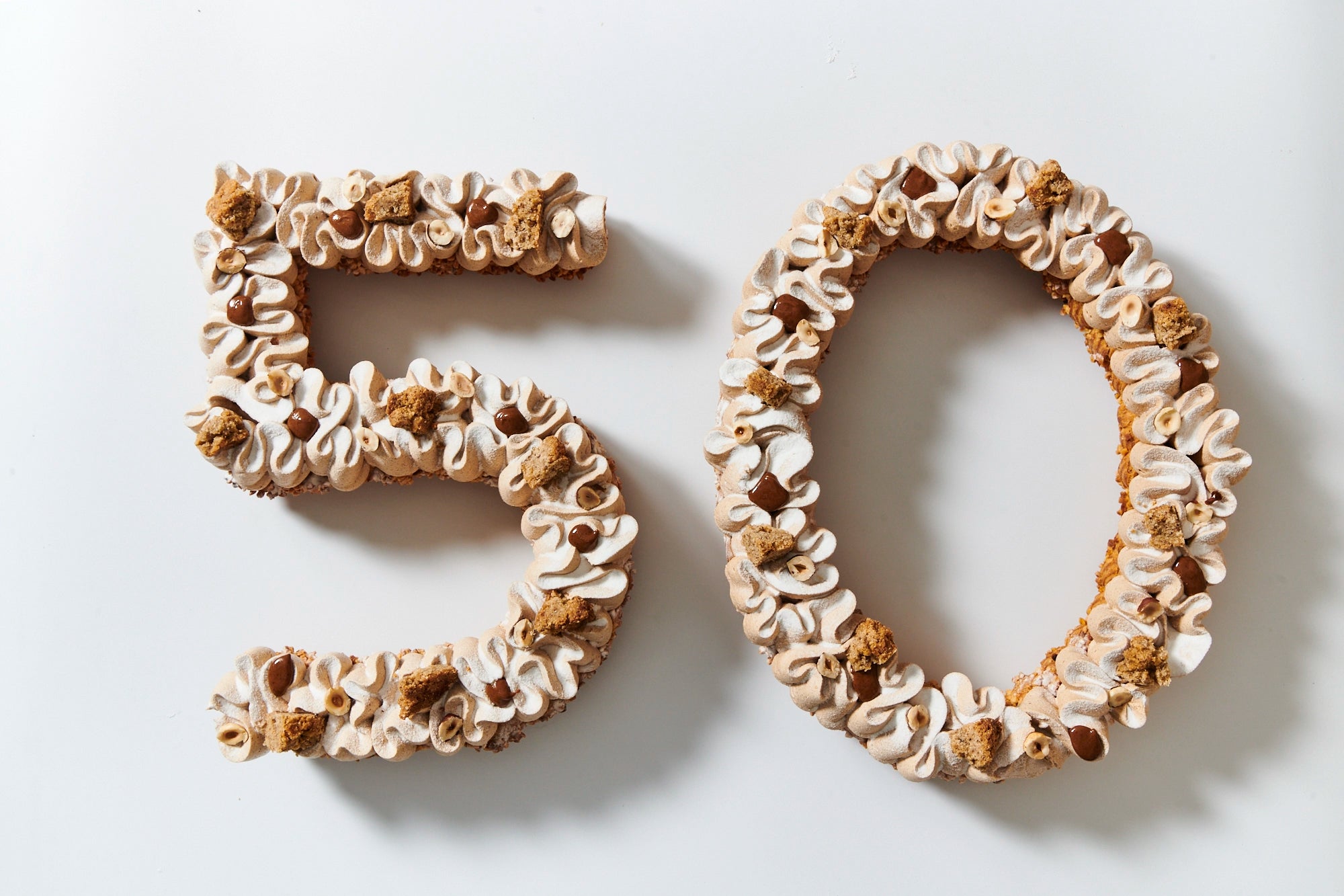 Number Cake géant en forme de chiffre 50 revisité façon Paris-Brest par le Chef Jeffrey Cagnes, avec crème mousseline praliné, noisettes torréfiées et éclats de chou pour un anniversaire ou événement à Paris.