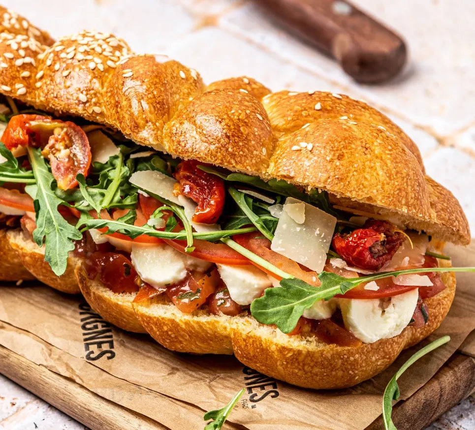 Gros plan sur la garniture du sandwich Veggie avec mozzarella fondant, tartare de tomates, olives noires et copeaux de parmesan.