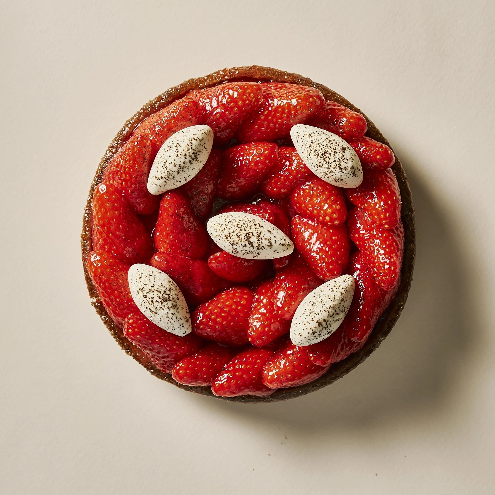 Vue du dessus d'une tarte aux fraises individuelle garnie de confit de fraises et de crémeux vanille.