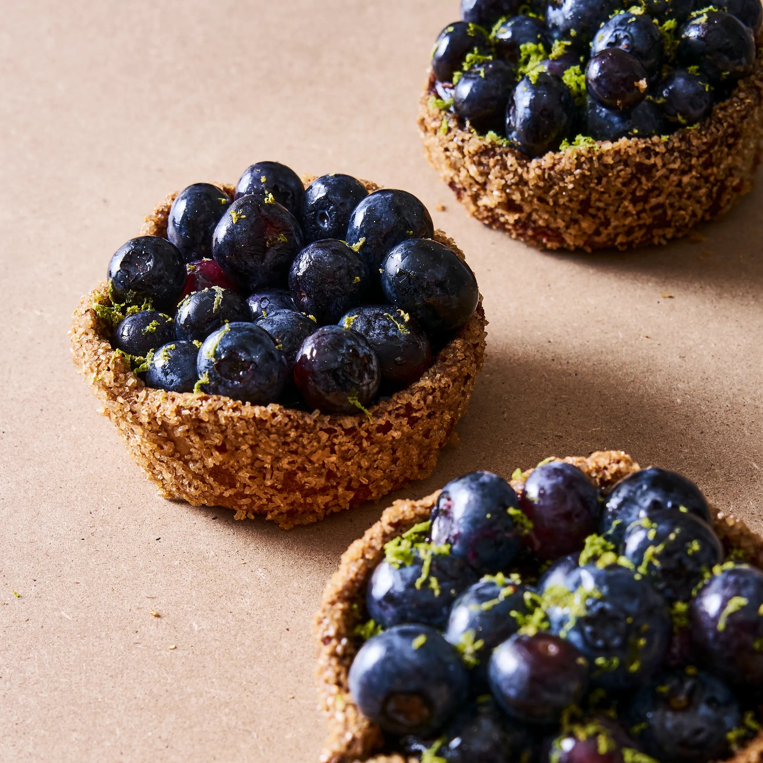 Sélection de tartelettes individuelles aux myrtilles et crémeux vanille.