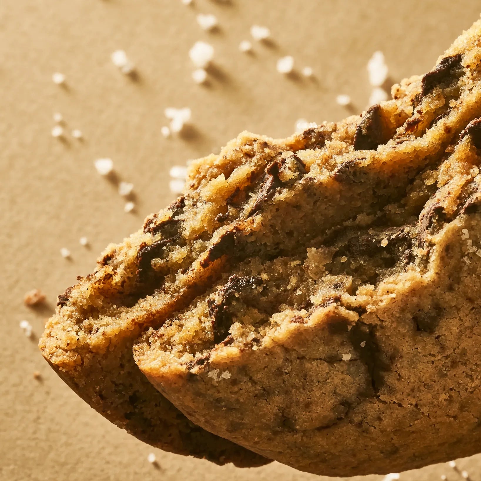 Coupe nette de deux moitiés de cookies superposées, dévoilant une mie incroyablement dense et un cœur de chocolat noir ultra-moelleux.