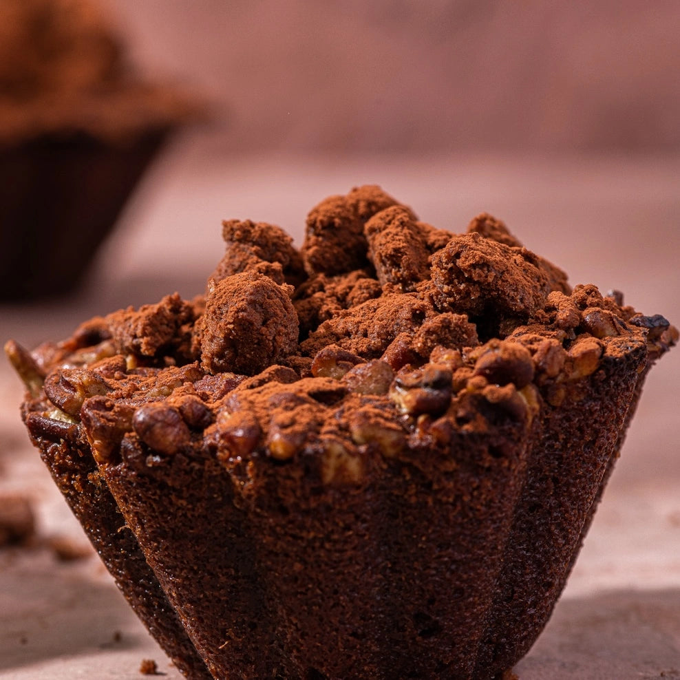 Brownie individuel au chocolat noir 64% surmonté d'un streusel croustillant et de noix de pécan saupoudré de cacao.