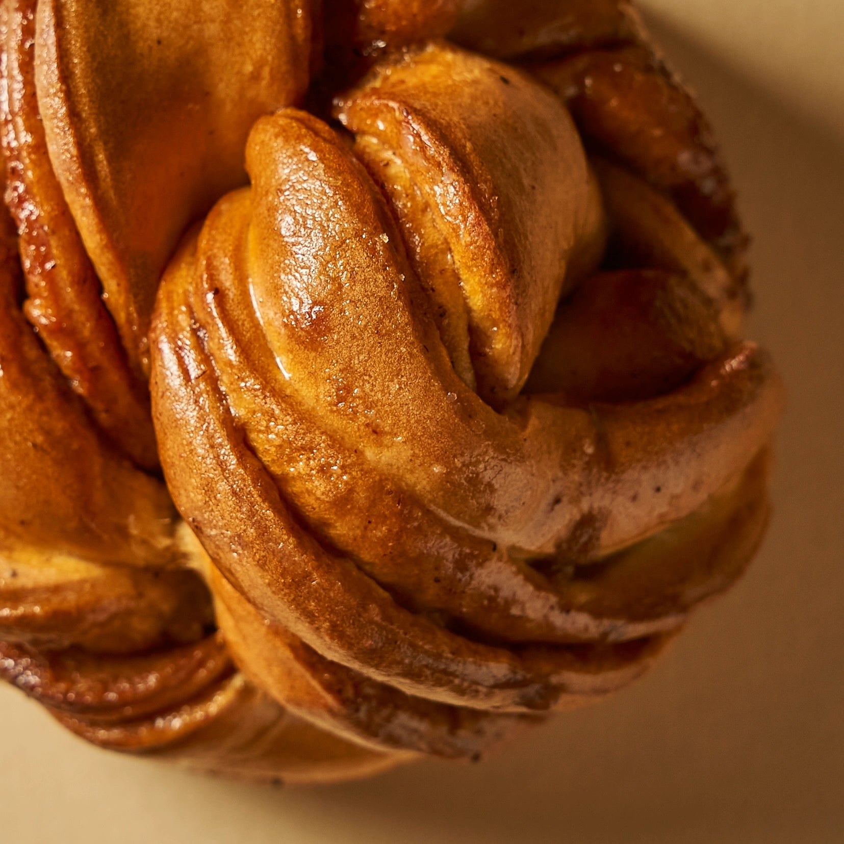 Gros plan sur le laquage brillant au sirop de miel et cannelle d'un cinnamon roll.
