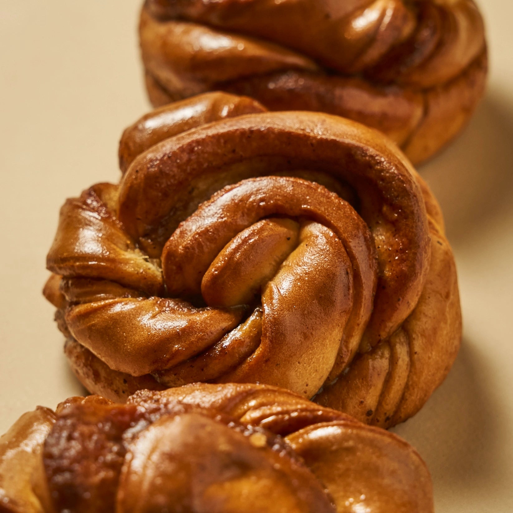 Alignement de trois cinnamon rolls dorés au sirop de miel et cannelle.