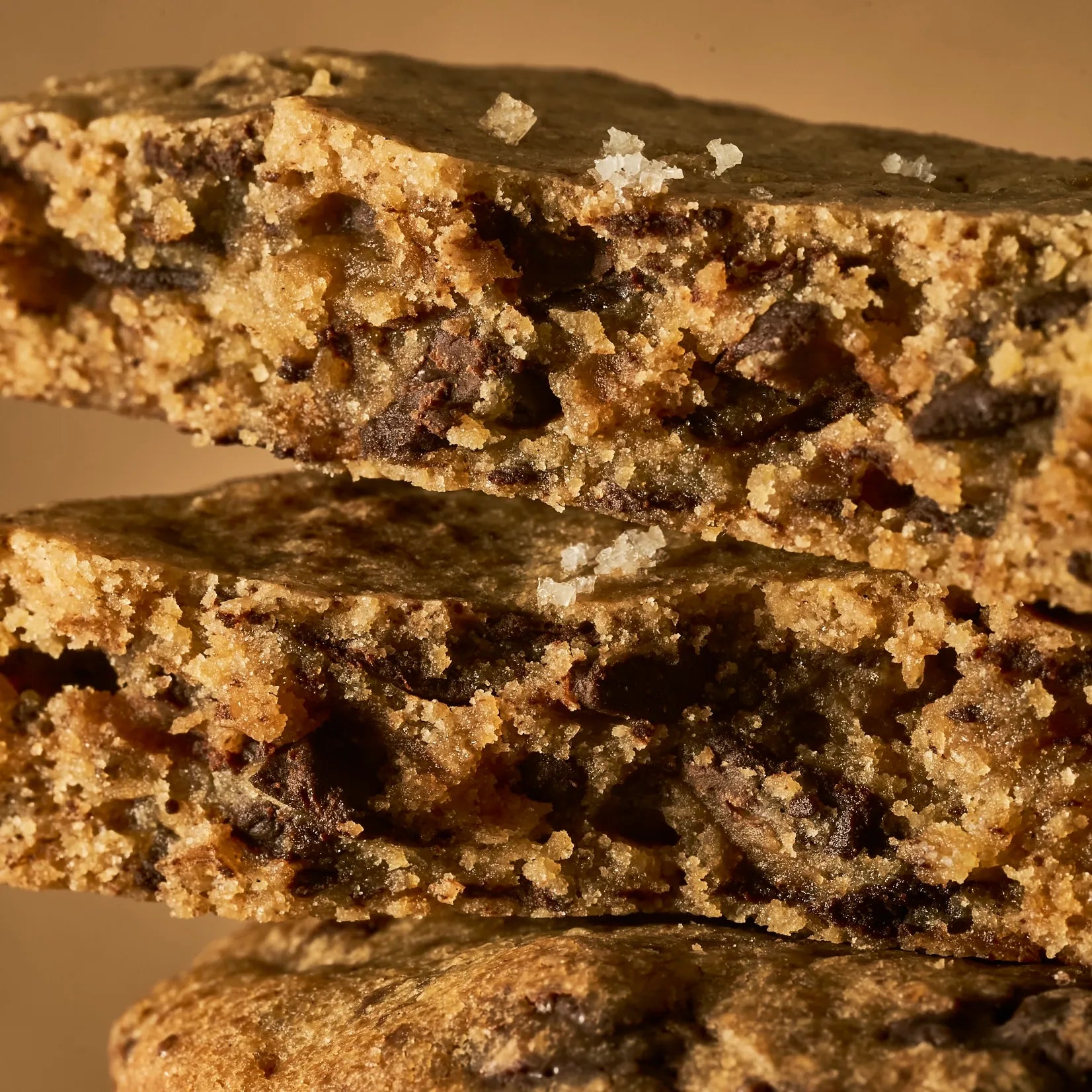 Gros plan macro sur la texture craquelée, croustillante et dorée d'un cookie au chocolat avec des cristaux de fleur de sel de Guérande.