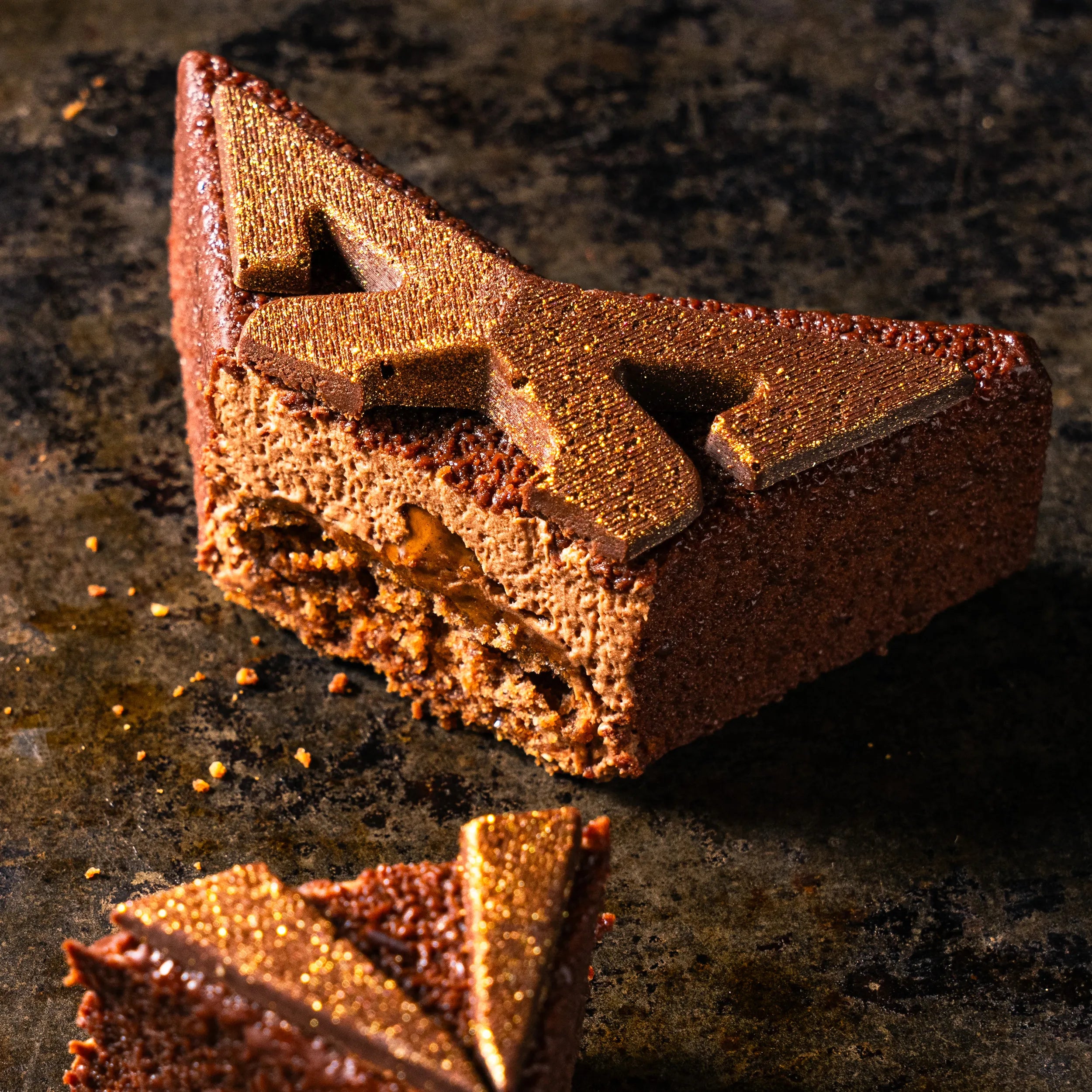 Coupe de l'entremets Cupra Chocolat montrant la superposition des textures : mousse au chocolat noir 64%, praliné amandes-noisettes et biscuit moelleux.