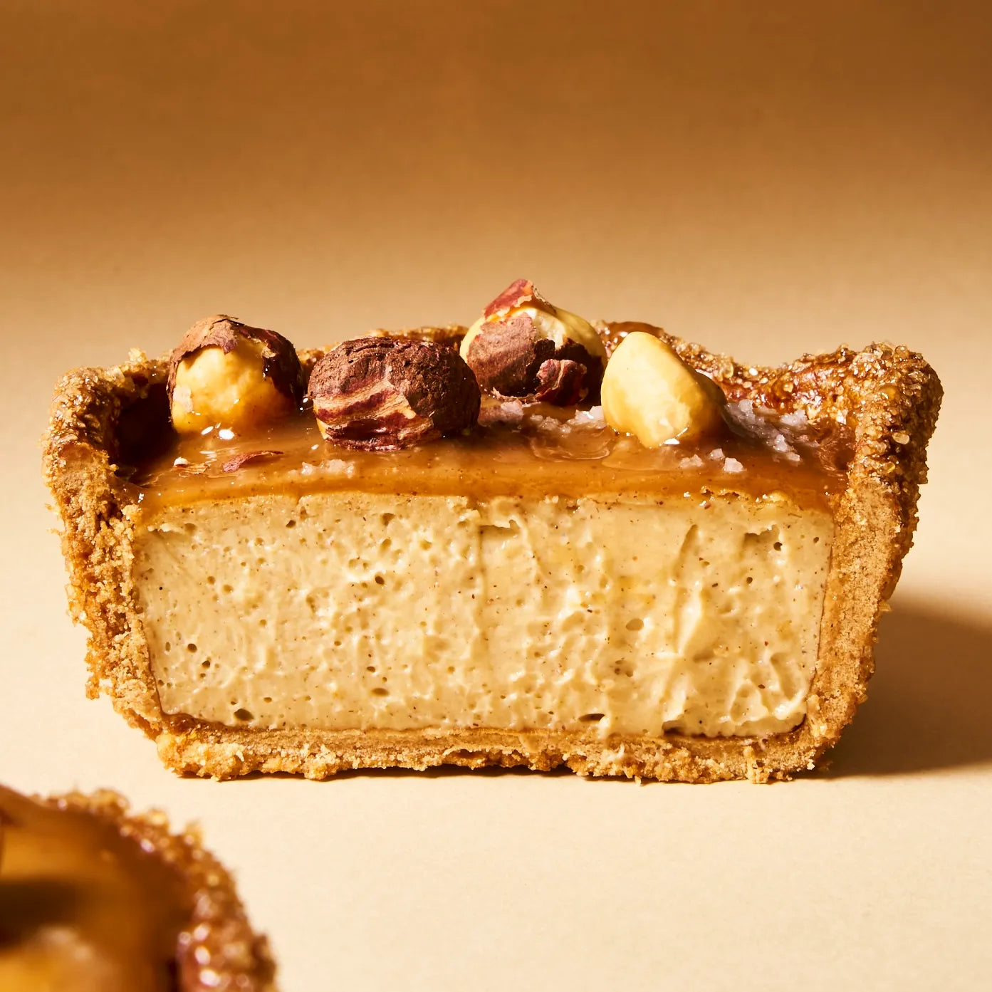 Coupe transversale d'un flan noisette Jeffrey Cagnes mettant en valeur la texture onctueuse du crémeux vanille sous une nappe de praliné.