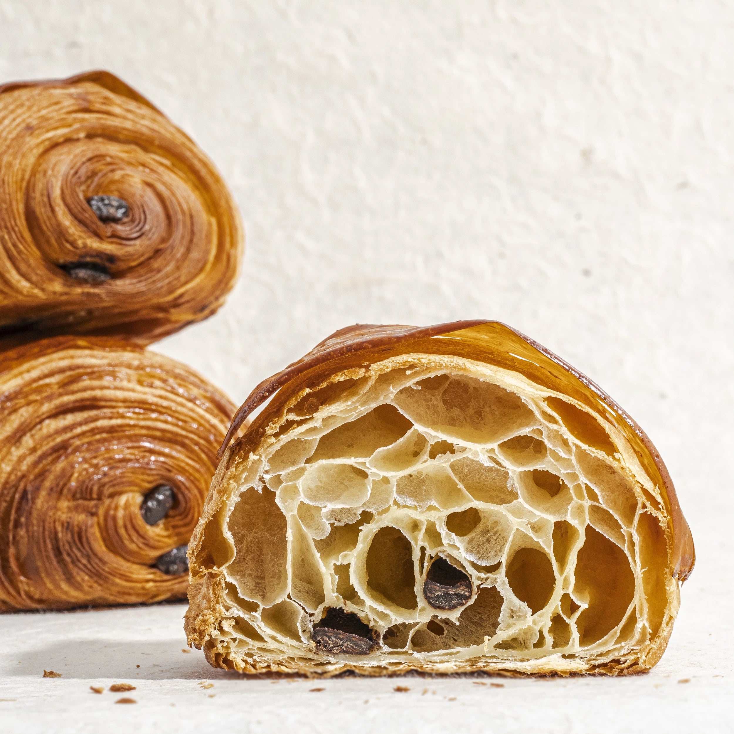 Pain au chocolat coupé en deux révélant un alvéolage parfait, une mie légère et deux barres généreuses de chocolat noir.
