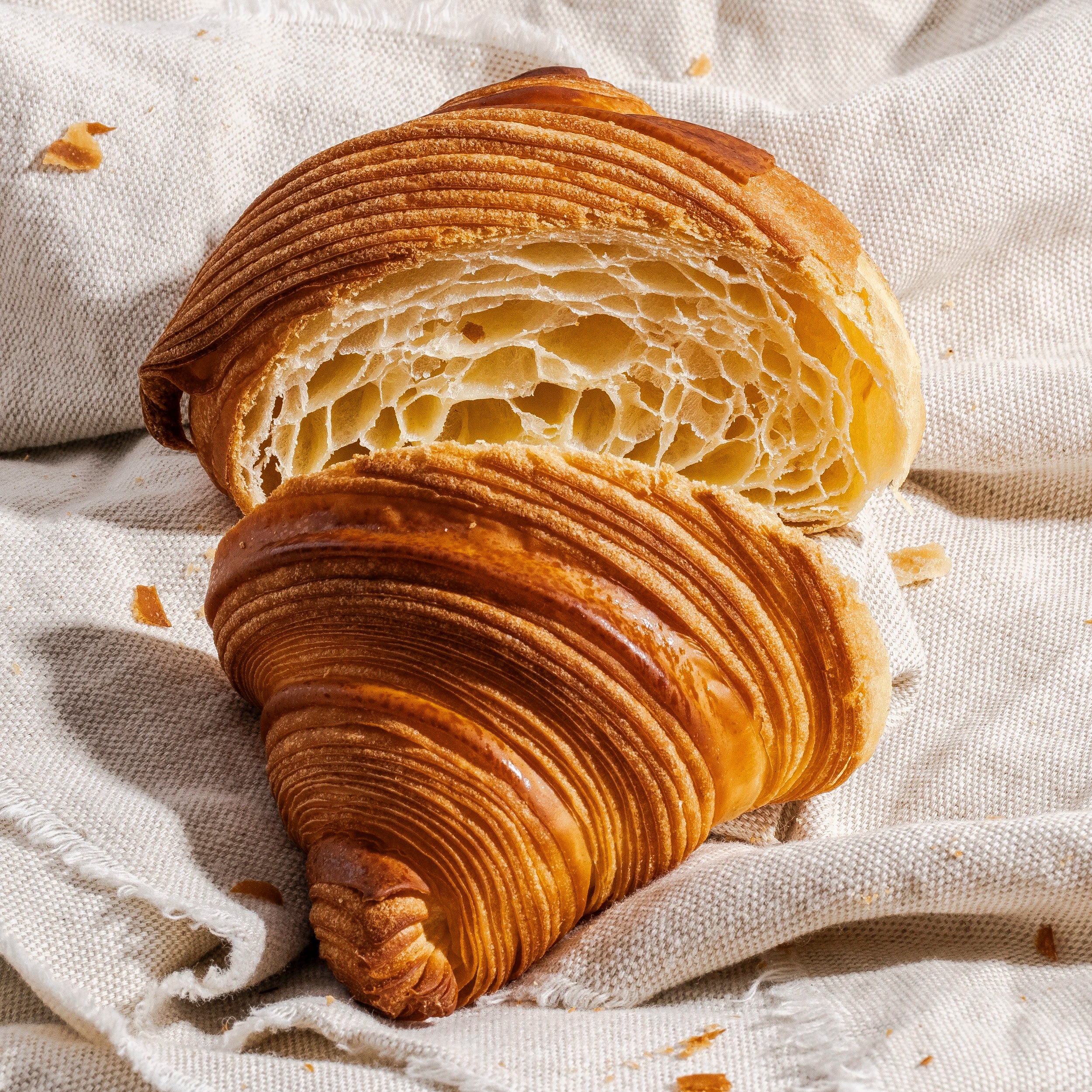 Un croissant croustillant coupé en deux révélant une mie alvéolée, idéal pour un petit-déjeuner artisanal à Paris.