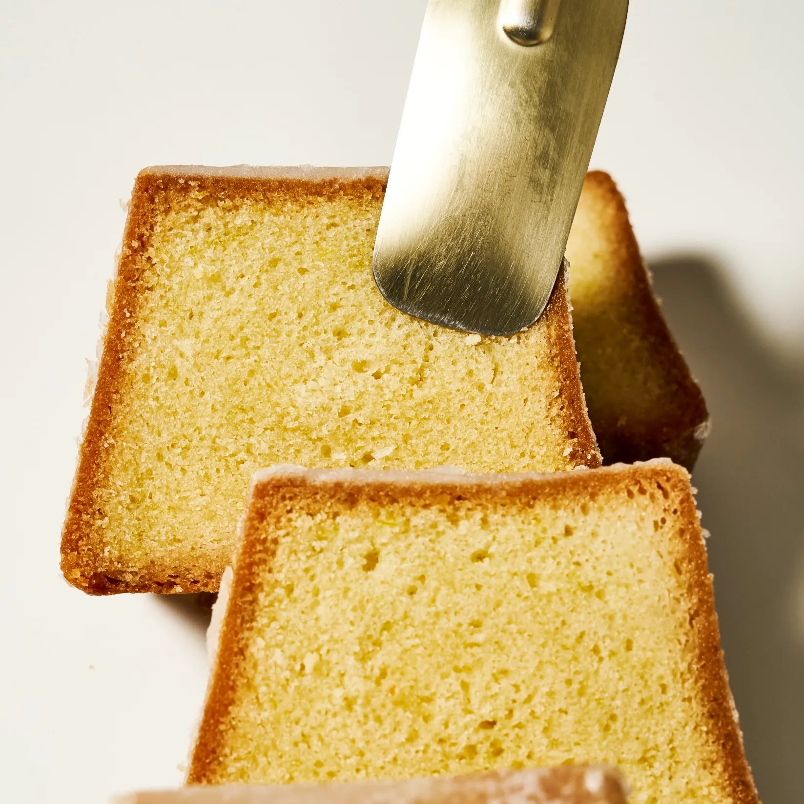 Gros plan sur la mie ultra-moelleuse et la croûte glacée d'une part de cake au citron vert signée Jeffrey Cagnes.
