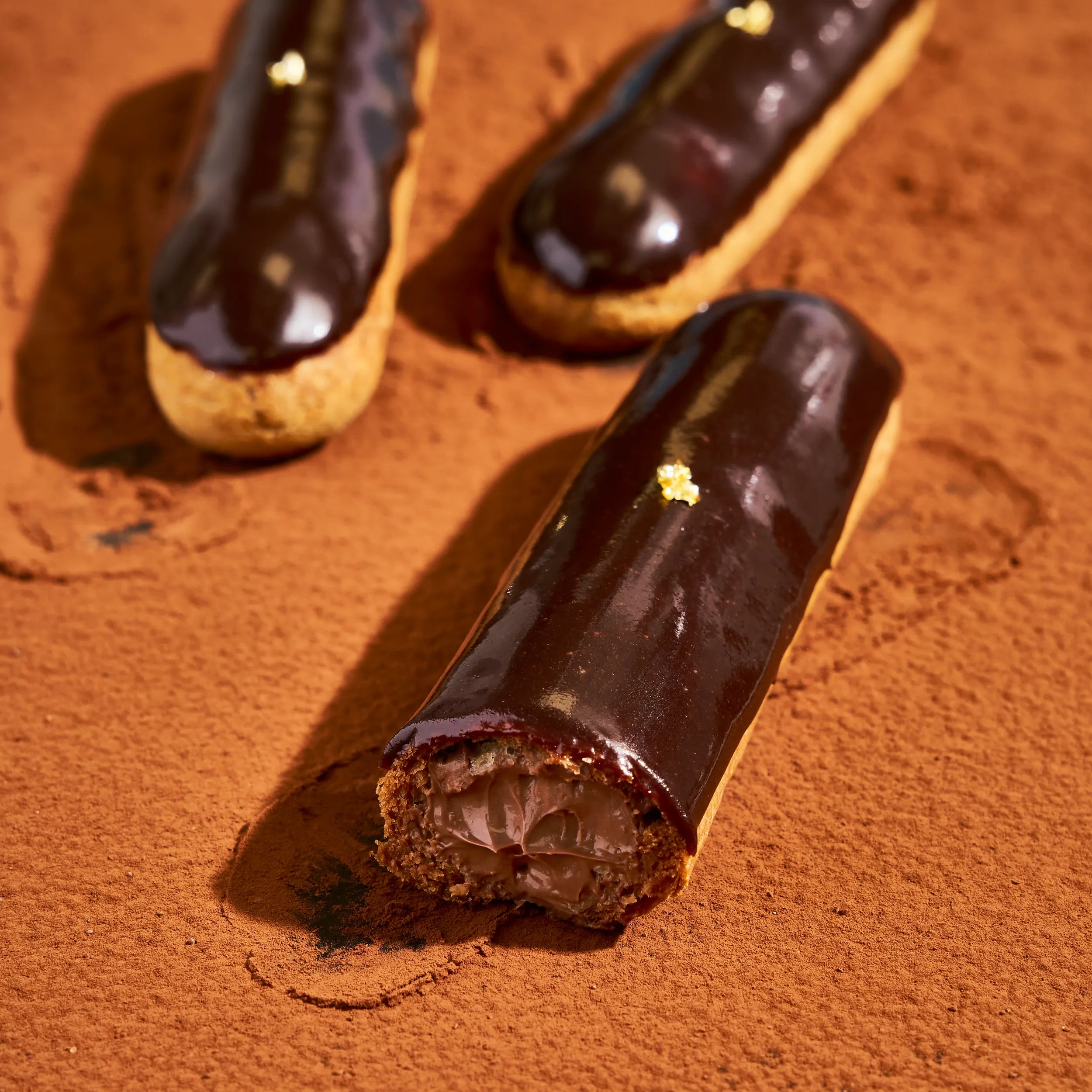Éclair au chocolat coupé en deux révélant la générosité du crémeux au chocolat noir du Pérou 64%.
