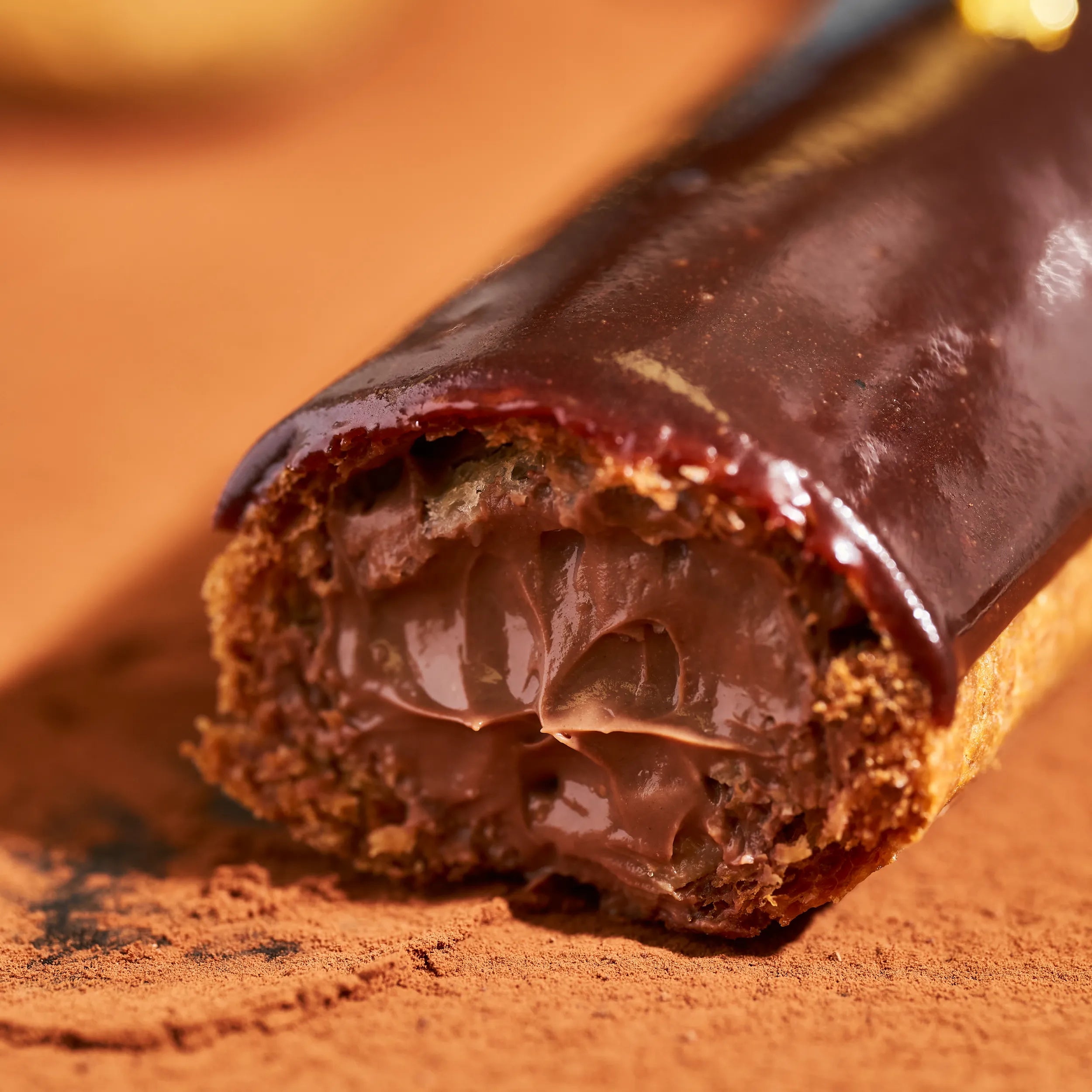 Gros plan sur la brillance du glaçage et la garniture onctueuse de l'éclair au chocolat Jeffrey Cagnes.
