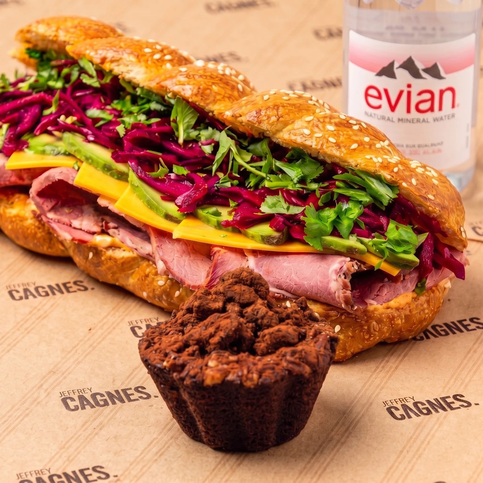 Formule Déjeuner complet comprenant le Sandwich Pastrami en pain Hallot, une bouteille d'eau Evian et une pâtisserie au chocolat sur papier Jeffrey Cagnes.