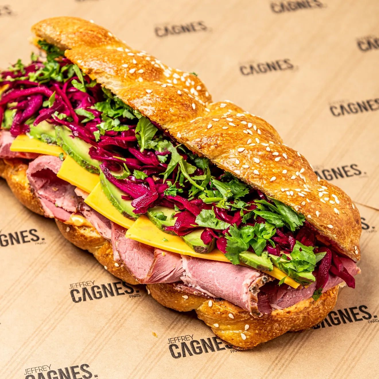 Gros plan en angle sur le sandwich Pastrami garni de chou rouge croquant, d'herbes fraîches et de cheddar.