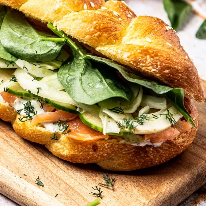 Gros plan sur la garniture fraîche du sandwich au saumon avec fenouil émincé, brin d'aneth et concombre croquant.