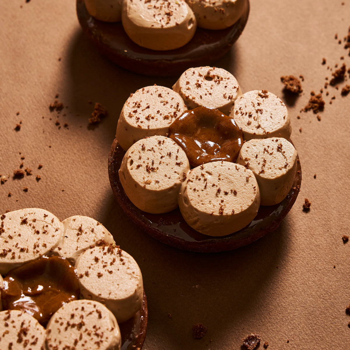 Tarte individuelle chocolat tonka de Jeffrey Cagnes en forme de fleur, avec pochage crème namelaka au chocolat au lait et cœur de praliné coulant.