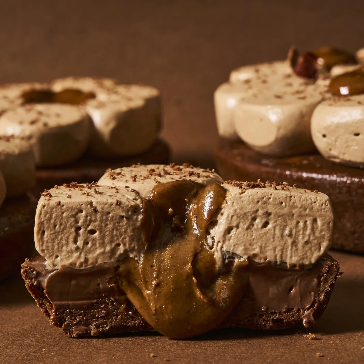 Vue en coupe spectaculaire de la tarte chocolat tonka révélant le praliné pur ultra-coulant et le crémeux chocolat noir 64%