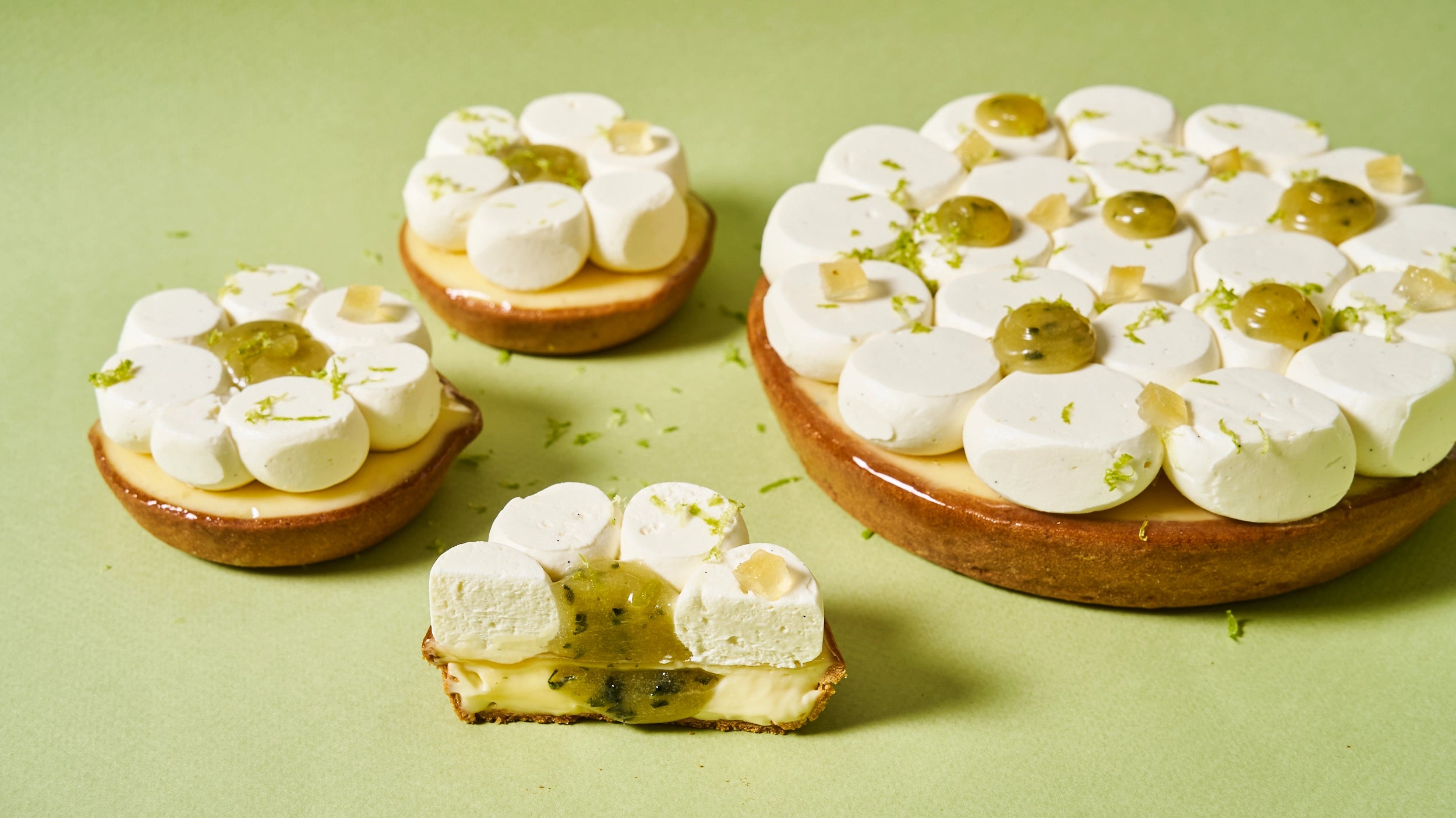 Présentation de la tarte au citron, huile d’olive et basilic de Jeffrey Cagnes en formats individuel et à partager, avec une part coupée révélant un cœur de gelée au basilic infusé sous des dômes de crème.