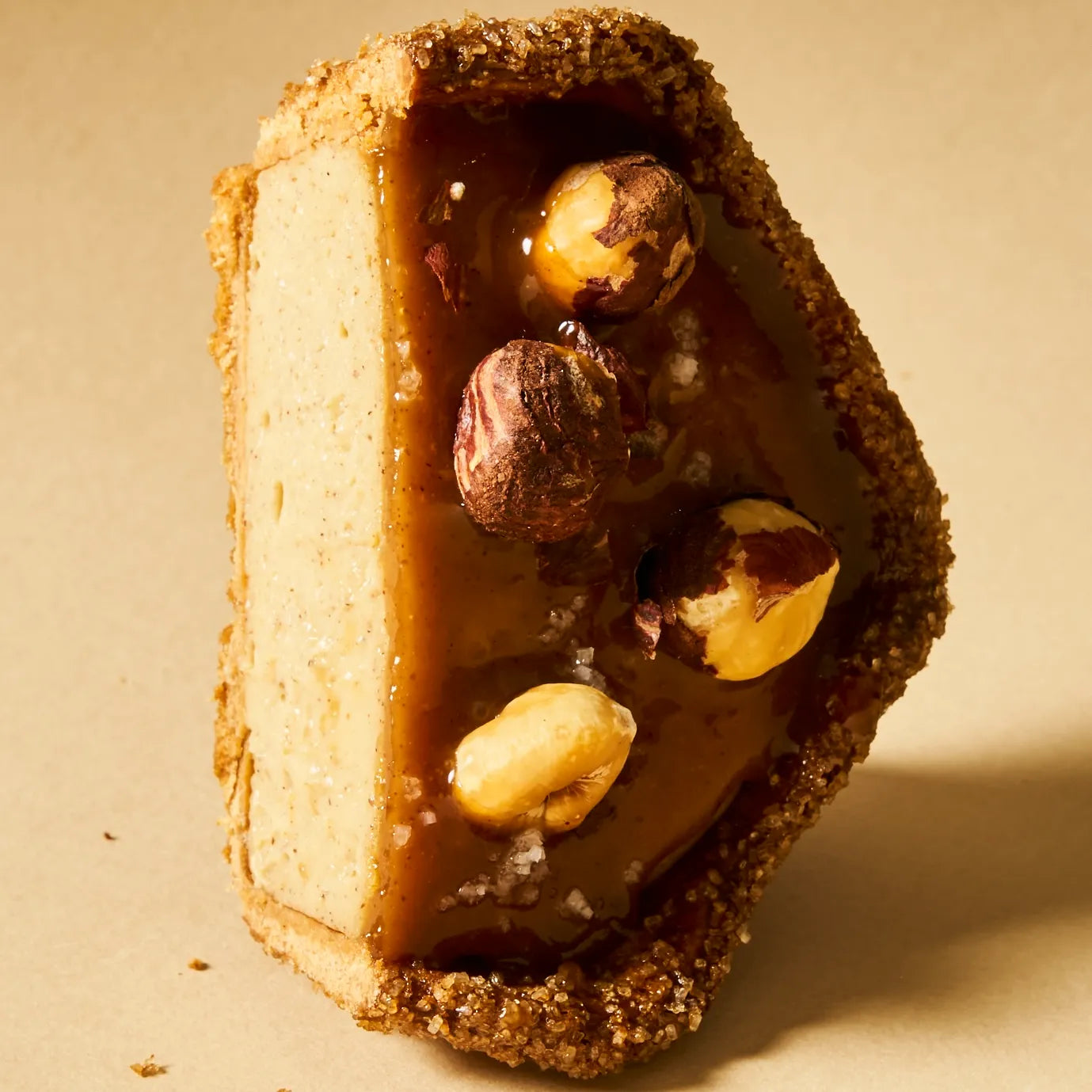 Plan vertical artistique d'une demi-part de flan noisette, soulignant le parfait équilibre des textures entre la pâte croustillante et le cœur fondant.