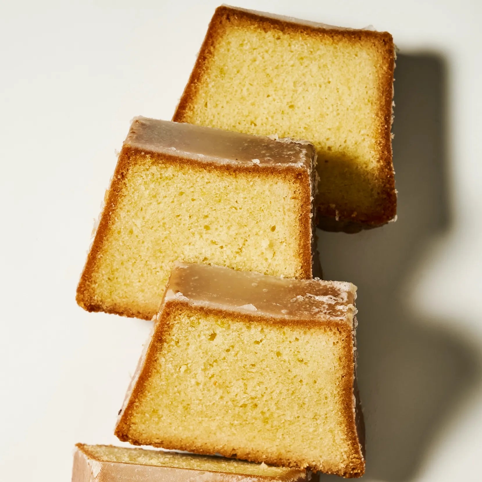 Alignement de plusieurs parts de cake au citron vert par Jeffrey Cagnes recouvertes d'un fin glaçage au sucre acidulé.