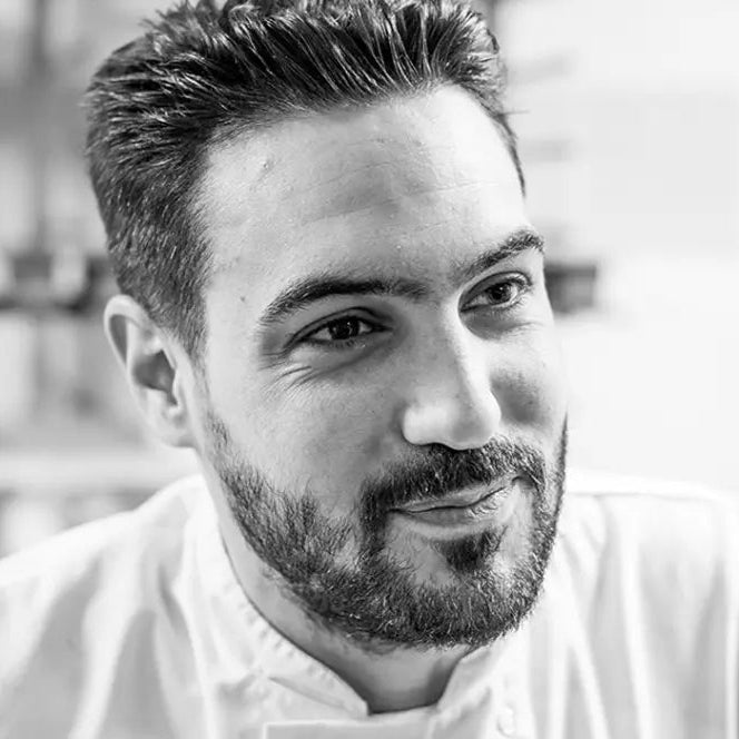 Gros plan du visage du Chef Pâtissier Jeffrey Cagnes, souriant légèrement, en veste blanche.